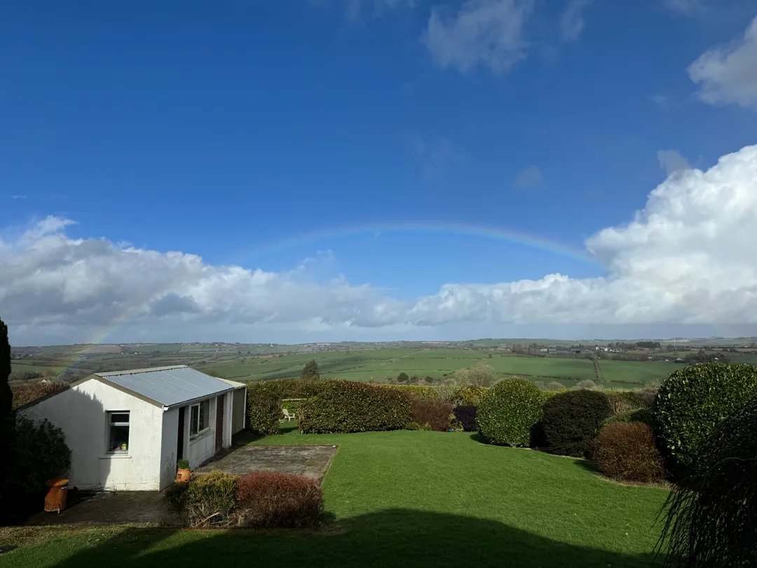 Our boutique kennel building with lush fields and a rainbow overhead